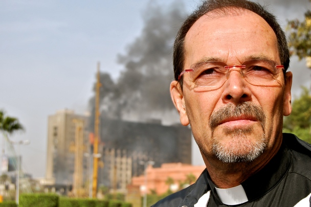Monsignore Joachim Schroedel, im Hintergrund brennende Gebude nach einem Anschlag in Kairo